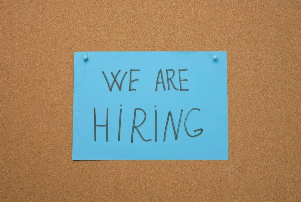 Blue sheet of paper with an inscription on a brown cork board. Recruitment concept, vacancy